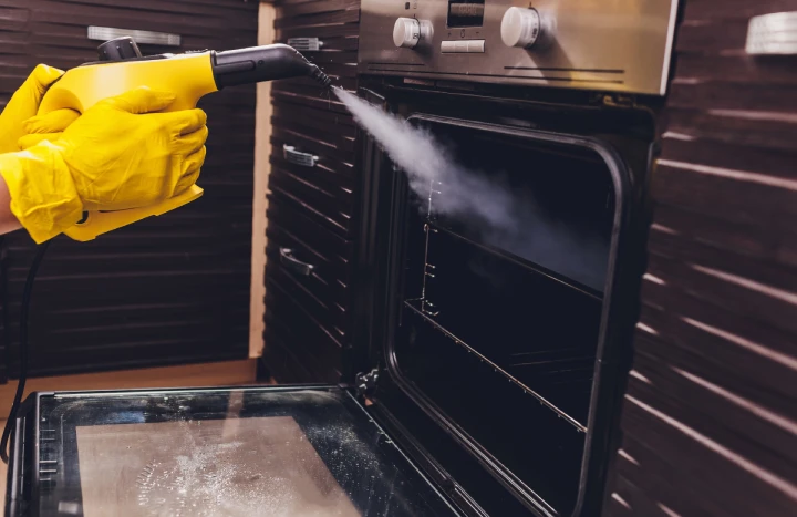 Steam cleaning the inside of a dirty kitchen oven.