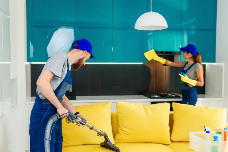 Professional cleaners vacuuming and dusting a kitchen.