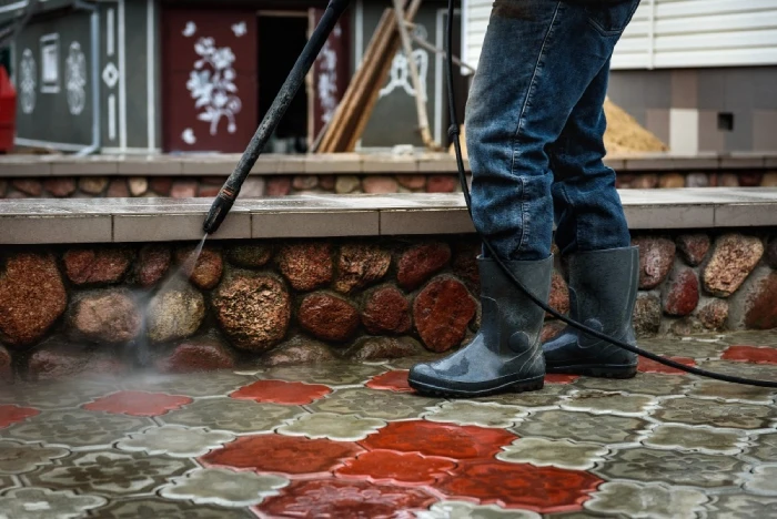 Pressure washing brick patio with water spray.