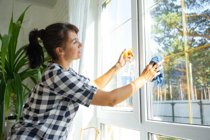 Woman spraying and wiping a glass window.